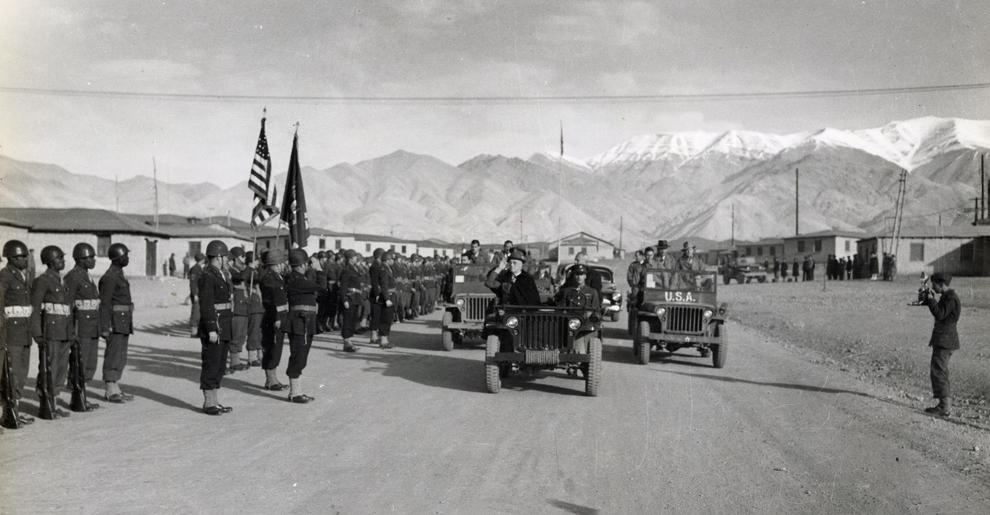 Roosevelt in a jeep passes by rows of soldiers at attention